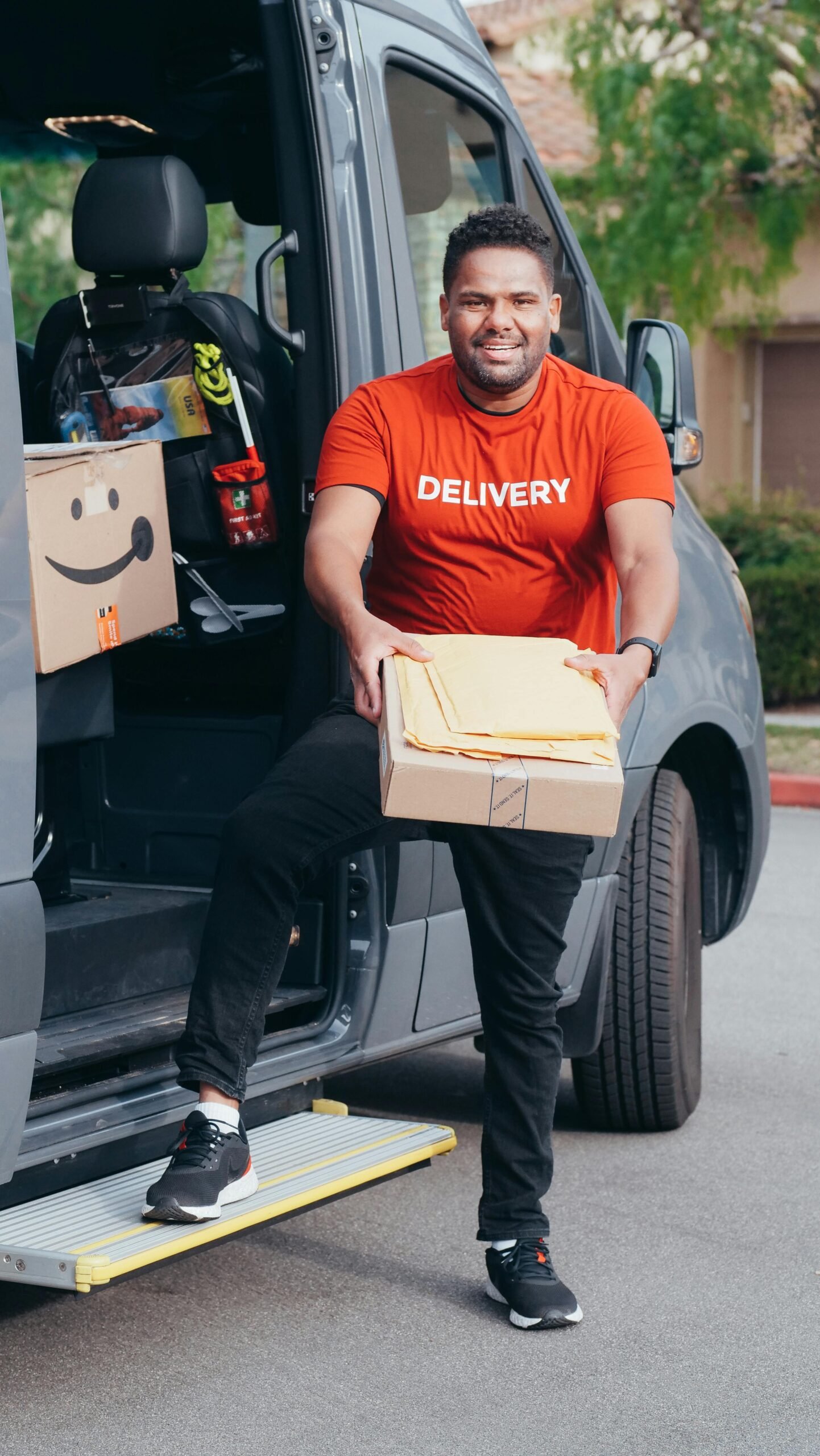 Happy delivery man stepping out of van holding a package.